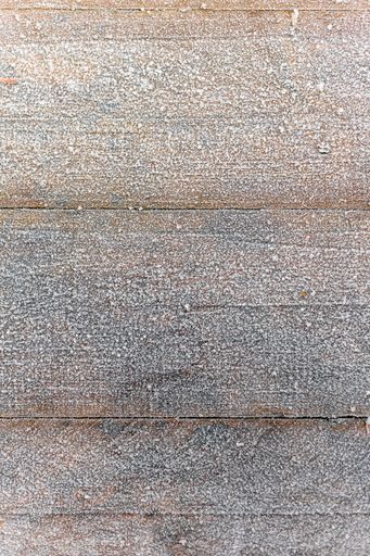 A vertical shot of a wooden floor covered in a thin layer of snow