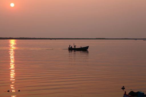 The silhouette of a boat sailing in the calm sea captured from the coast at sunset