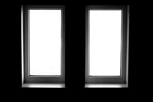 A closeup of two long windows in greyscale from inside of a room