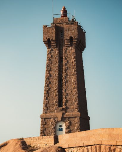 A vertical shot of Phare de Men Ruz against blue sky in bright sunlight, Perros-Guirec, France