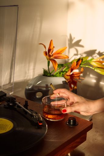 Woman's Hand Holding THC CBD Joint and Whiskey Glass at a record player.