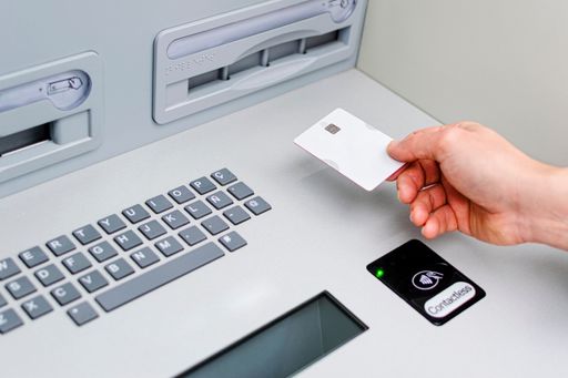 A man uses Contactless technology at an ATM with his credit card to view his bank account