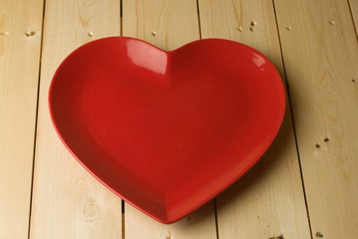 A red heart-shaped plate on a wooden table
