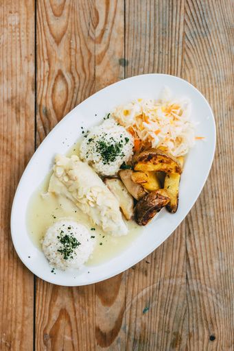 A vertical closeup of the chicken with almonds, rice, baked potatoes and coleslaw.
