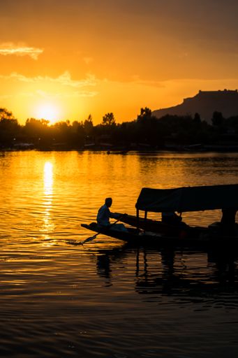 A breathtaking shot of a small boat's and some people's silhouettes on a beautiful sunset background