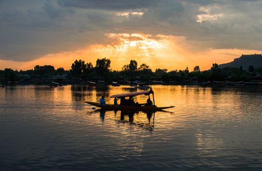 A breathtaking shot of a small boat's and some people's silhouettes on a beautiful sunset background