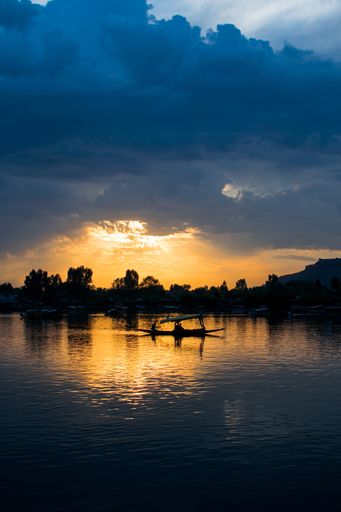A breathtaking shot of a small boat's and some people's silhouettes on a beautiful sunset background