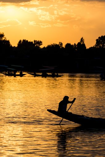 A breathtaking shot of a human silhouette sitting on a boat nose on a beautiful sunset background