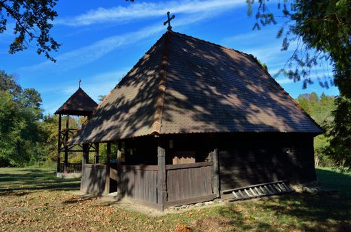 A view of a wooden building with a cross in a village