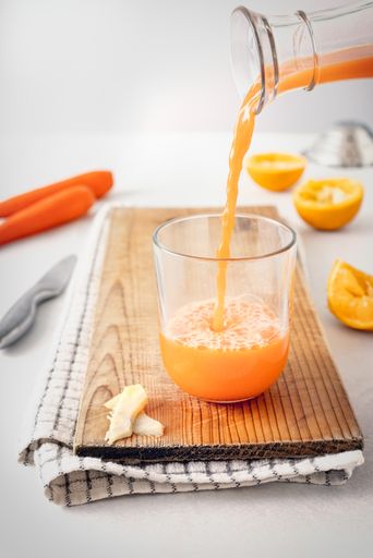 A closeup vertical shot of a fresh-squeezed orange juice glass poring from a transparent bottle- perfect for fresh-squeezed juice concept