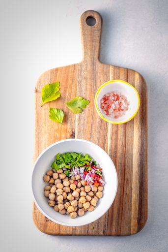 A vertical shot of two plates with salad ingredients on a wooden board isolated on grey background