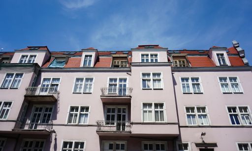 A low angle shot of the residential building with balconies under a blue sky