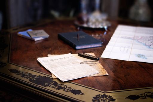 A high angle shot of the sheet of paper and a map on a wooden table