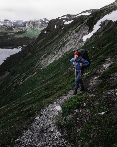 A vertical shot of a female hiker walking on a mountain path