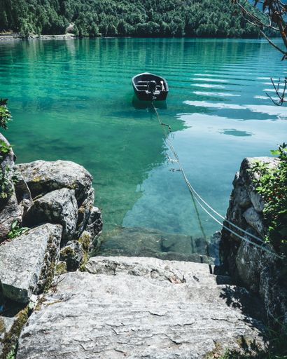A vertical shot of a lake with crystal clear blue water and a boat ready for a trip