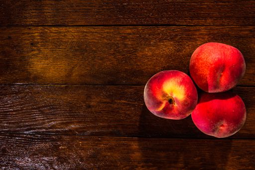 A top view of fresh red juicy peaches on a rustic wooden table