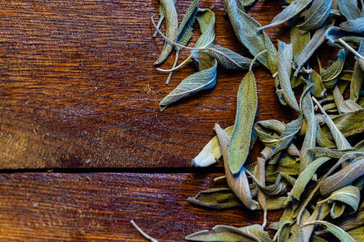 A top view of green dry leaves of sage (salvia) on a wooden board