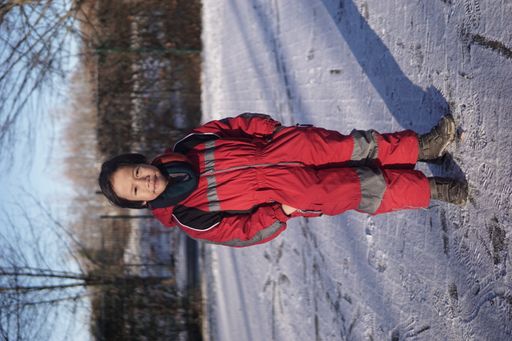 A handsome Southeast Asian boy posing on a winter day wearing a red snow jacket outdoors