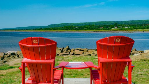 A closeup shot of muskoka chairs near a lake in Nova Scotia, Canada