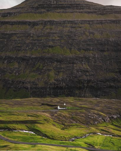 A vertical shot of a beautiful mountainous landscape with a hut in Saksun, Faroe Islands