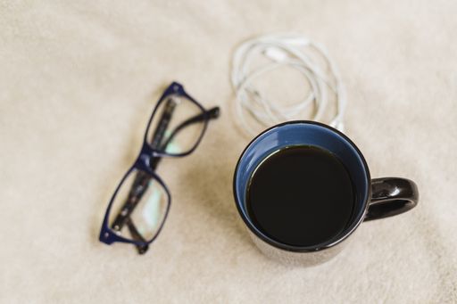 A closeup shot of a  cup of a cup of black coffee, and glasses isolated on a white background