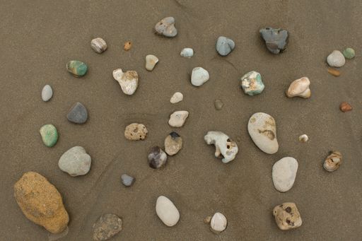 Top view of stones in different colors and shapes on sand