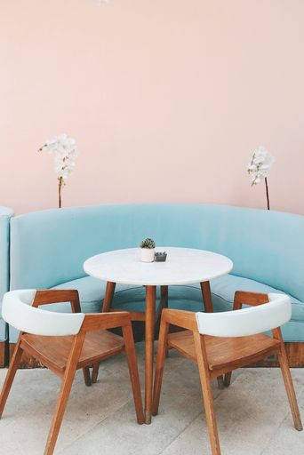 A colorful shot of modern light blue sofa, white wooden table , wooden chairs and white flowers