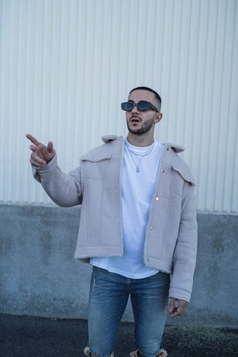 A portrait of a handsome confident Spanish man wearing sunglasses and posing outdoors