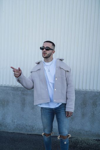A portrait of a handsome confident Spanish man wearing sunglasses and posing outdoors
