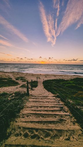 A vertical shot of a pathway through the sea during sunset