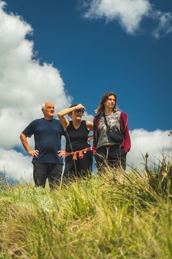 A group of Argentinian man and women at a hilly meadow under a cloudy blue sky