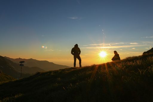 A silhouette of male and female enjoying the sunrise on the mountains