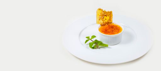 A creme brulee and caramel flake on a white plate isolated on a white background