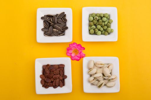 Tet Holiday, Lunar new year, chinese new year concept . Dried sunflower, lotus, watermelon and pumkin seeds top view isolated on yellow. Tet snacks