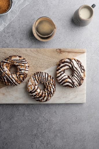 A vertical top view of chocolate cream donuts on a messy kitchen table