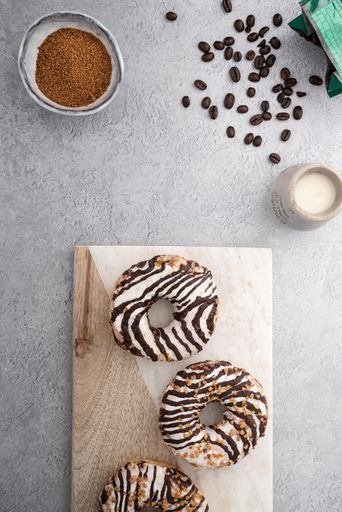 A vertical top view of chocolate cream donuts on a messy kitchen table