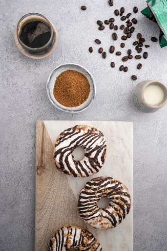 A vertical top view of chocolate cream donuts on a messy kitchen table