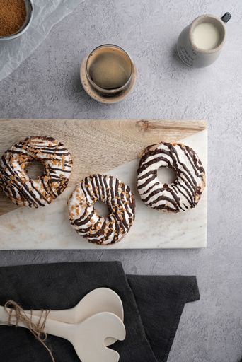 A vertical top view of chocolate cream donuts on a messy kitchen table