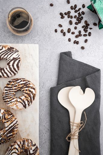 A vertical top view of chocolate cream donuts on a messy kitchen table