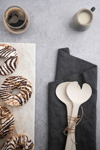 A vertical top view of chocolate cream donuts on a messy kitchen table