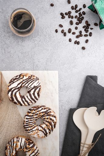 A vertical top view of chocolate cream donuts on a messy kitchen table