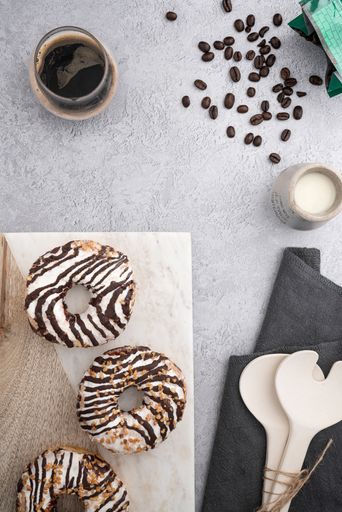 A vertical top view of chocolate cream donuts on a messy kitchen table