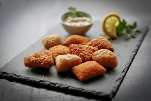 A closeup shot of fried potato cheese balls or croquettes over dark stone background.