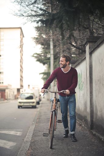 A vertical shot of a young male riding a bicycle on the sidewalk
