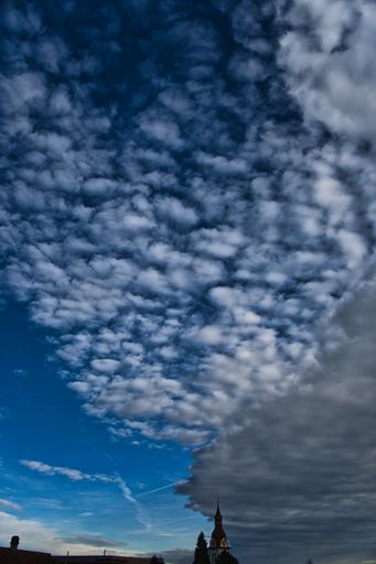 A vertical shot of a blue sky with some clouds