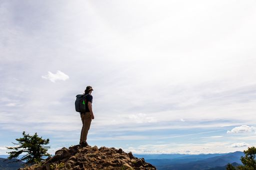 A closeup shot of a man looking into the distance on the top of the mountain on a sunny day
