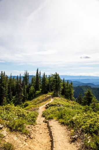 A vertical shot of a trail along mountain ridge stretching into the distance on a sunny day