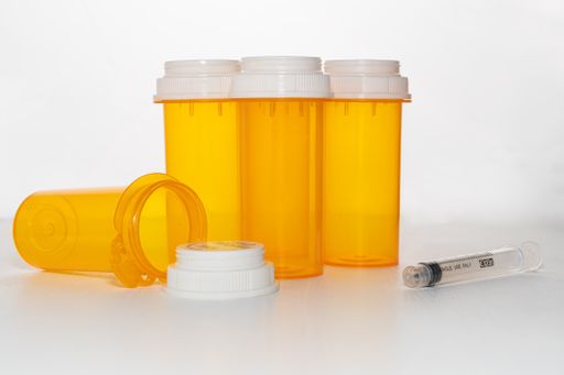 A closeup shot of empty medicine bottles and syringe
isolated on a white surface