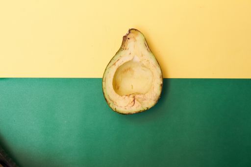 A top view of a sliced half of an avocado on green and yellow background