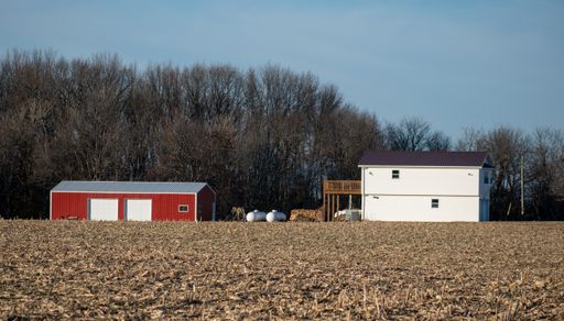 A scenic view of a farm house in a forest on a sunny day